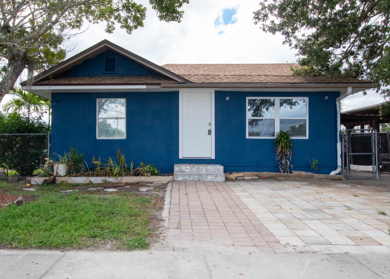 Blue house exterior with white trim, front steps and a paved approach