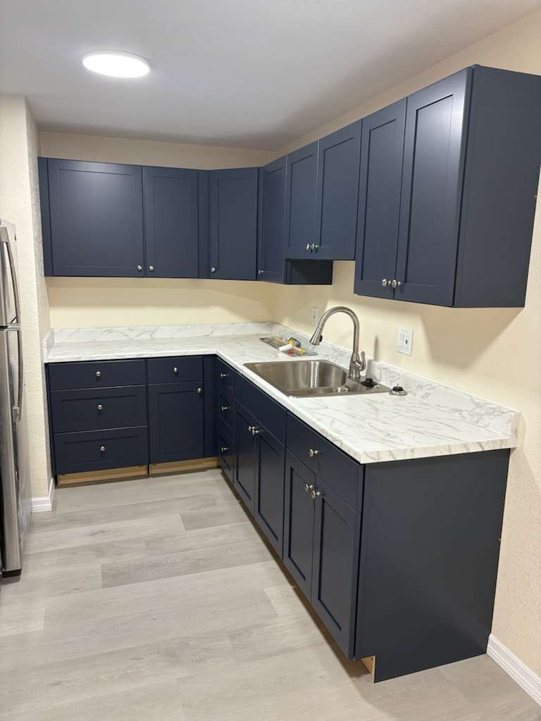 Kitchen with navy cabinets, light countertops and a double sink